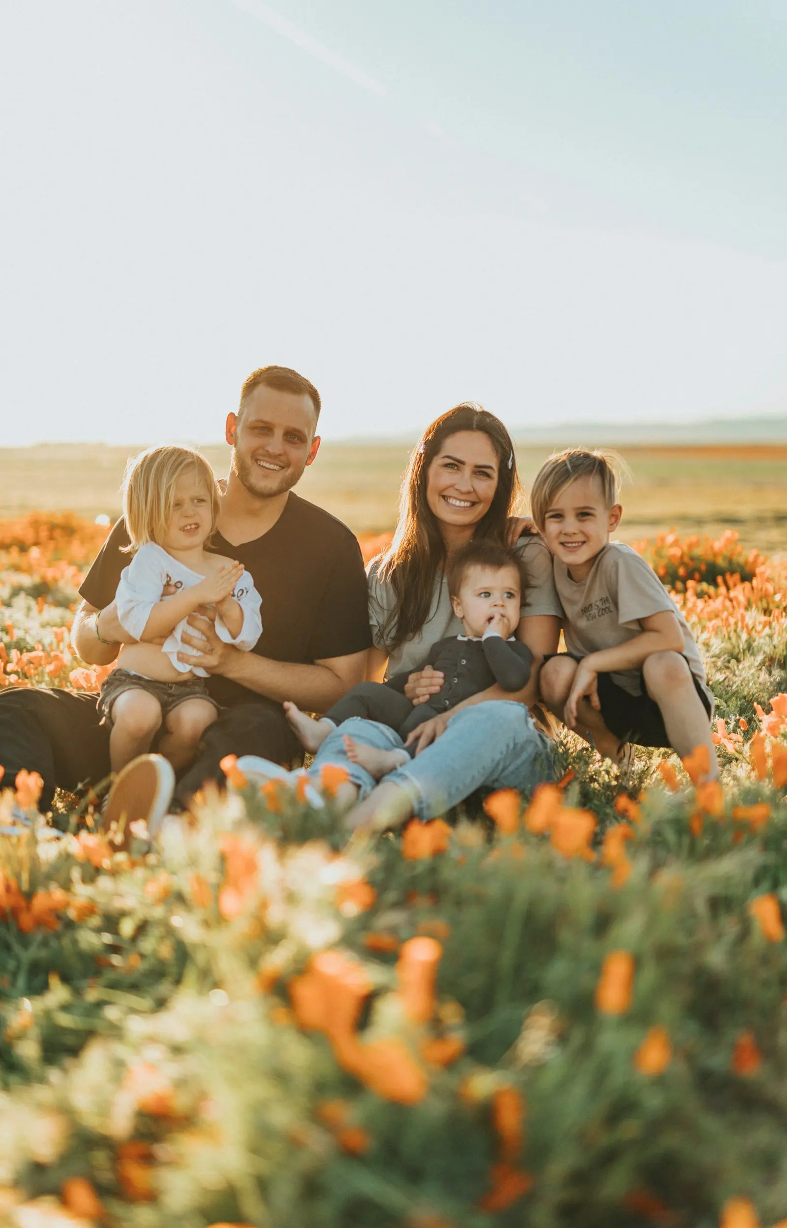 Familia con tres hijos sentada al aire libre en un campo de flores